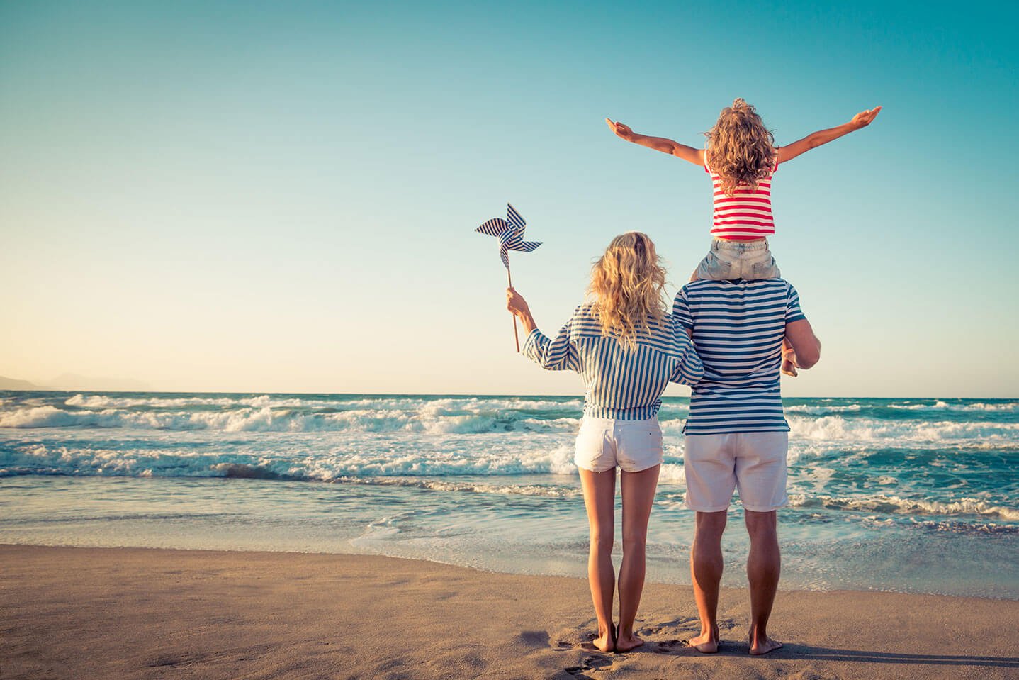 Couple looking out over ocean with happy child